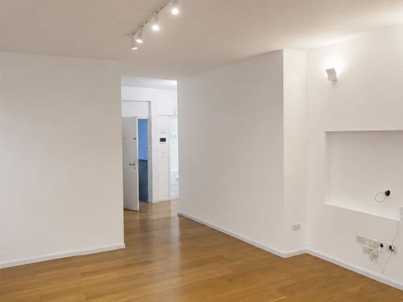 After: open-plan room with white walls and a wooden floor