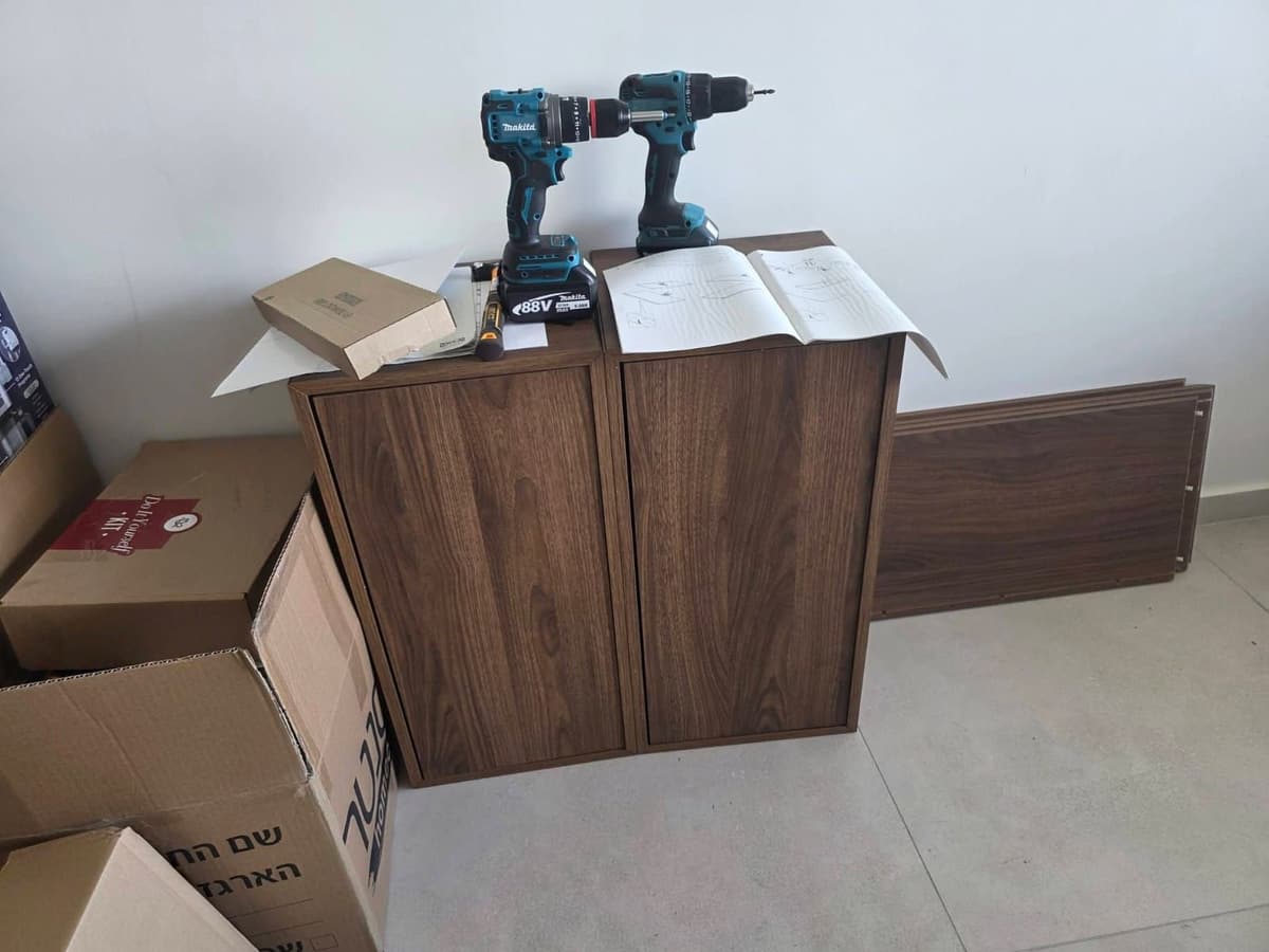 Wooden cabinet part-way through assembly, with cordless drills and the instructions on top