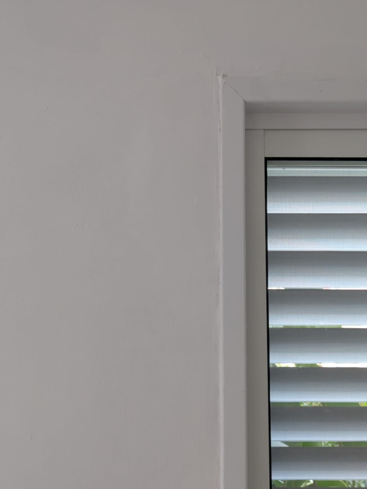 The wall beside the window, smooth and painted white