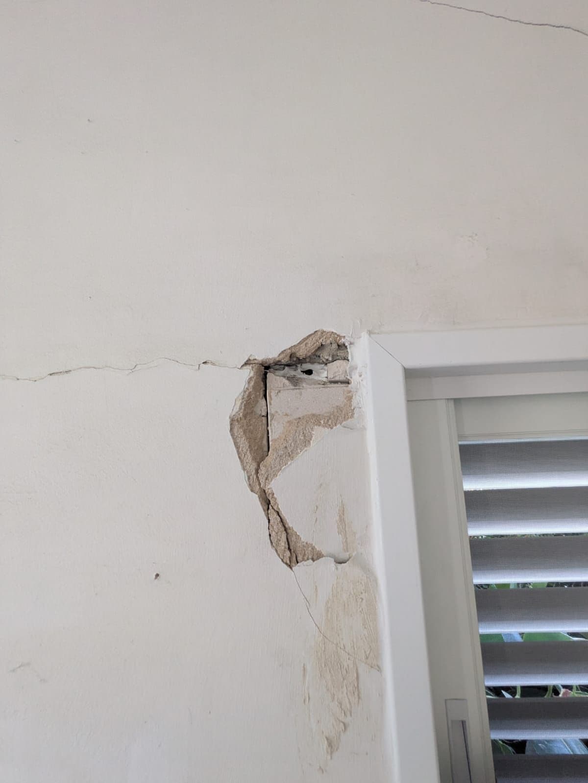 Crack and broken plaster beside a window
