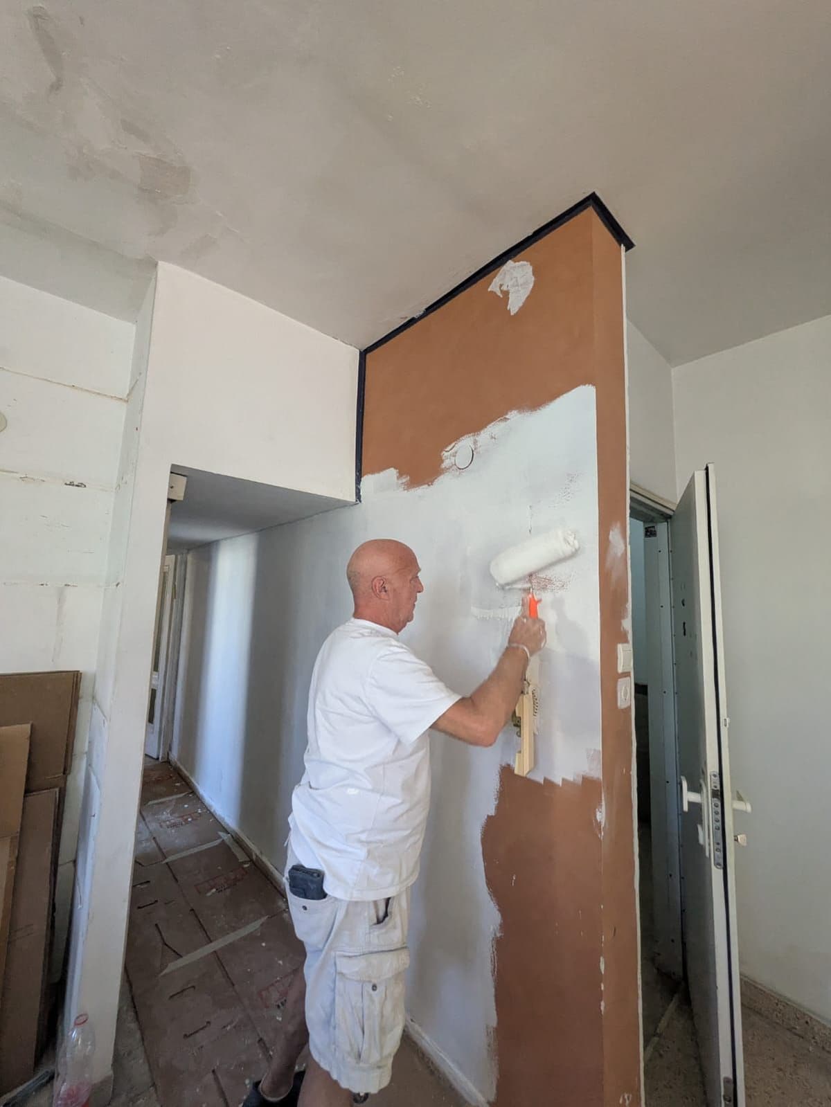 Oy Vey team member rolling white paint onto a board wall