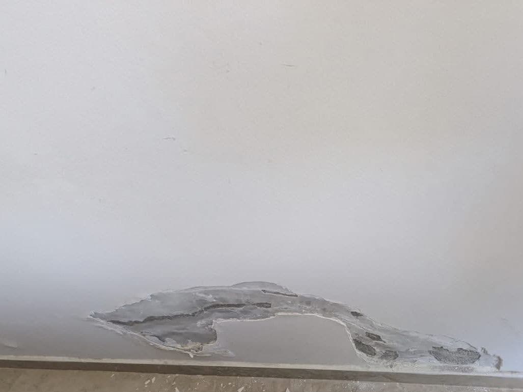 Flaking paint and plaster at the bottom of a wall