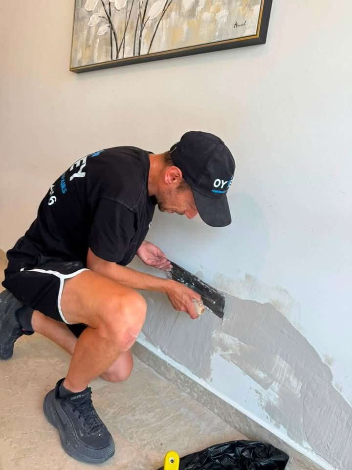 Oy Vey team member applying filler to a wall with a trowel